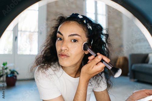 Beauty blogger applying makeup on cheek photo