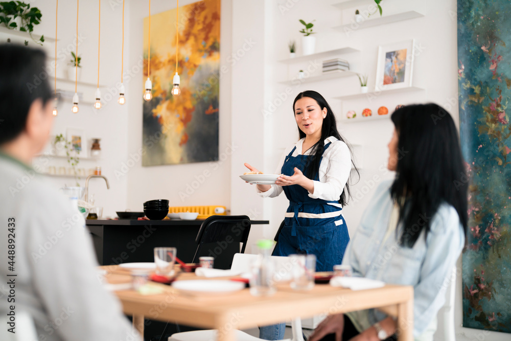 Smiling woman serving food for Asian friends