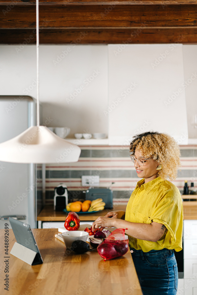Woman watching video on tablet while cooking in kitchen Woman watching video on tablet while cooking in kitchen