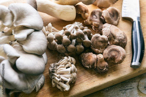Variety Of Mushrooms On Cutting Board With Knife photo