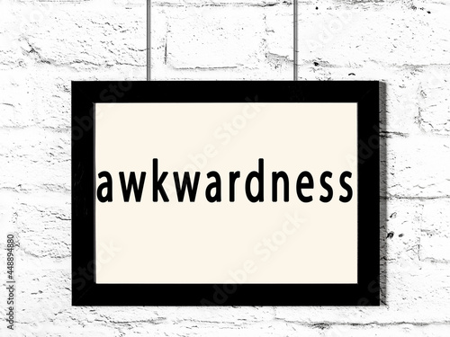 Fotografie Black frame hanging on white brick wall with inscription awkwardness