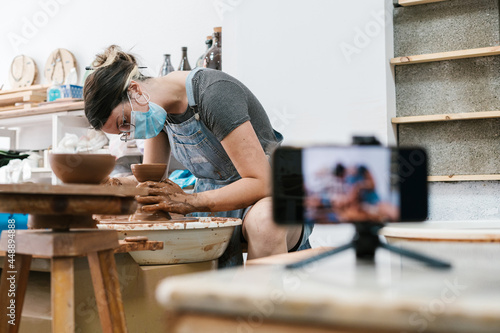 Highly concentrated craftswoman creating on the lathe photo