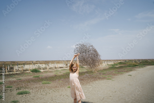 Girl with dry tumbleweed on summer day