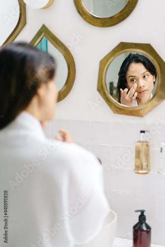 Asian female applying cream in morning photo