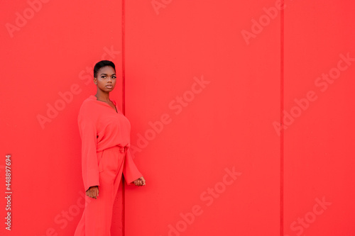 Beautiful Female With Electric red Suit Against Red Wall photo