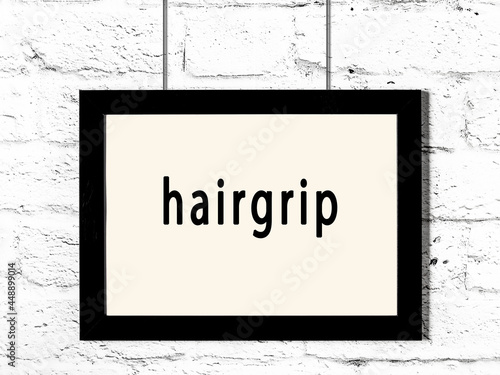 Black frame hanging on white brick wall with inscription hairgrip