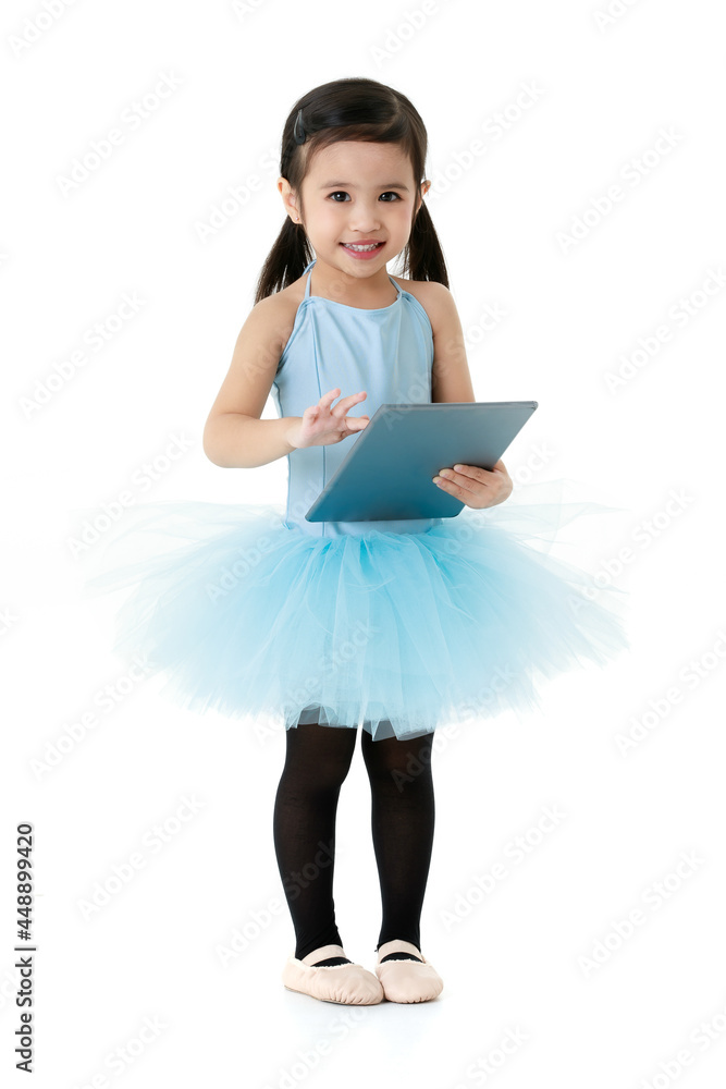 Portrait isolated studio shot of little Asian preelementary pigtails ballerina dancer girl in blue tutu ballet dress standing smiling look at camera holding and touching tablet on white background Portrait isolated studio shot of little Asian preelementary pigtails ballerina dancer girl in blue tutu ballet dress standing smiling look at camera holding and touching tablet on white background