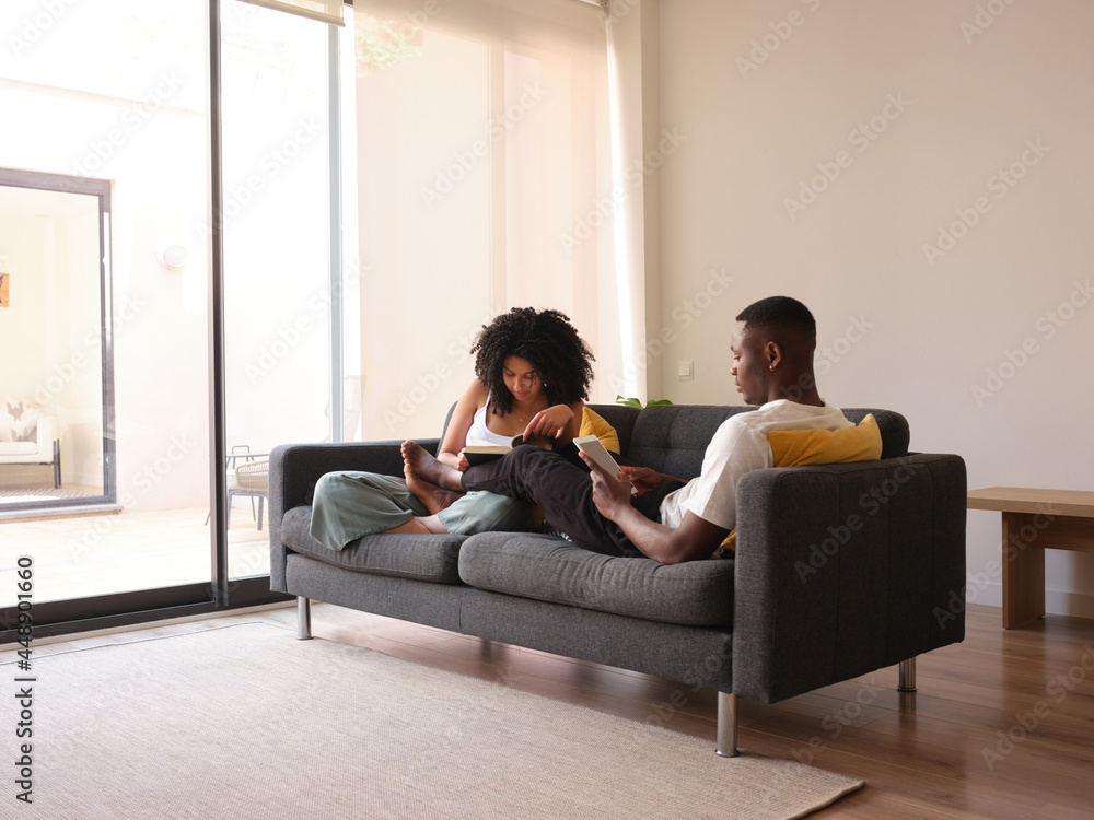 Black couple spending free time on couch. Black couple spending free time on couch.
