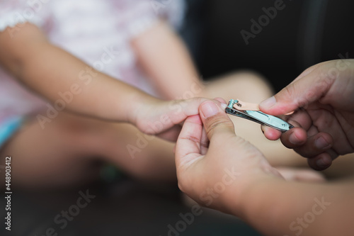 Closeup mother hands holding clippers cutting fingernails for her baby.