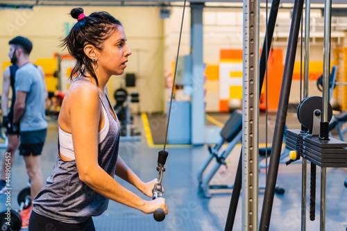 Fotografie young hispanic latina woman in a gym doing triceps on the pulley