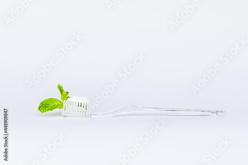 Toothbrush toothpaste and peppermint on white background.