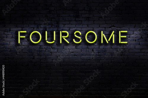 Neon sign. Word foursome against brick wall. Night view photo