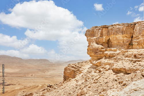 Makhtesh Ramon - Ramon Crater in Israel's Negev Desert from the Mitzpe Ramon lookout, with Mount Ramon in the background. View of color sand, stone Negev desert down from cliff