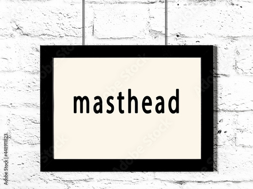 Black frame hanging on white brick wall with inscription masthead