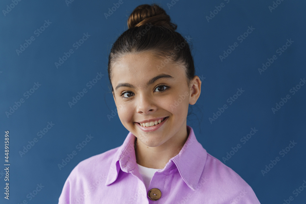 Close-up view, positive teenage girl smiling beautifully, looking at camera. Cute little girl on a blue background Close-up view, positive teenage girl smiling beautifully, looking at camera. Cute little girl on a blue background