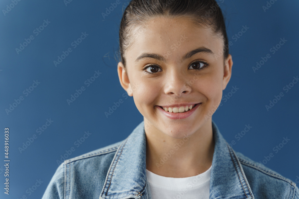 Close-up view, positive teenage girl smiling beautifully, looking at camera. Cute little girl on a blue background Close-up view, positive teenage girl smiling beautifully, looking at camera. Cute little girl on a blue background