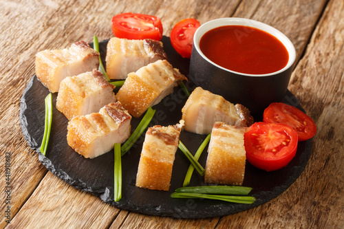 Lechon kawali crispy pan-fried pork belly, is a tasty Filippino food closeup in the slate dish on the table. Horizontal photo