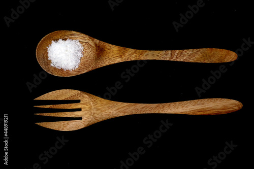 Flat lay Salt on the grunge rustic vintage wooden spoon and fork in black background