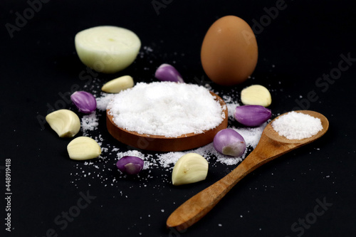 Seasoning Salt, onion, egg, and wooden spoon in black background