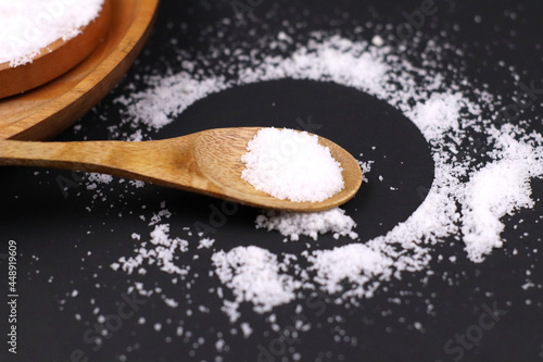 Wooden spoon has salt on it and surrounded by the circle shape of salt