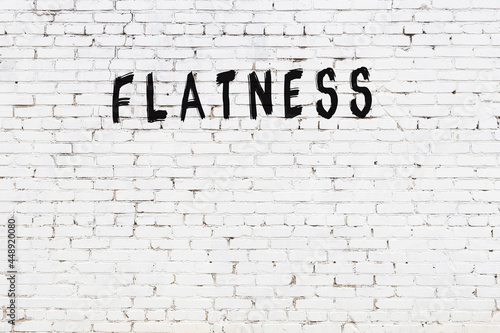 White wall with black paint inscription flatness on it