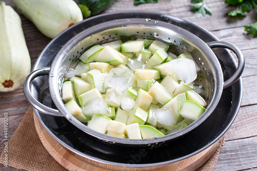 Valokuva Boiled vegetables, zucchini in a colander in ice water after blanching