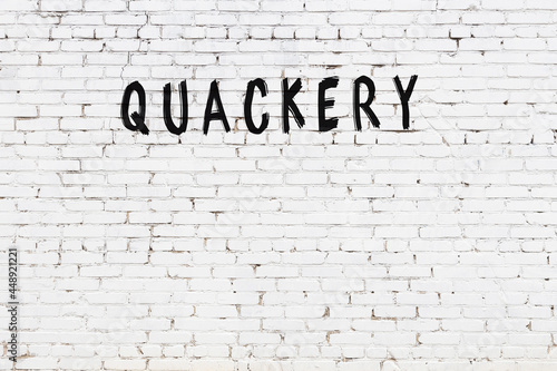 Inscription quackery painted on white brick wall