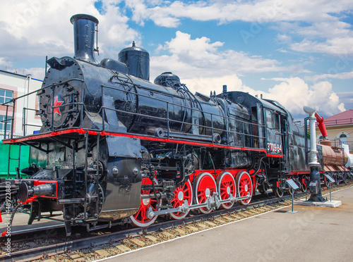 Heavy powerful Sovetsky Steam locomotive. Colored steam locomotive on a black and white background.