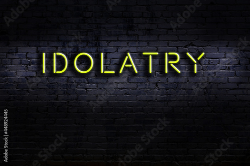 Night view of neon sign on brick wall with inscription idolatry photo