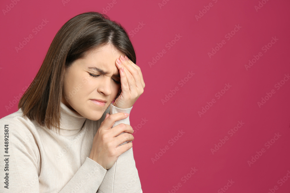 Young woman suffering from migraine on crimson background. Space for text Young woman suffering from migraine on crimson background. Space for text