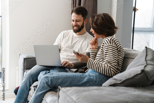 Happy young white couple looking at laptop computer