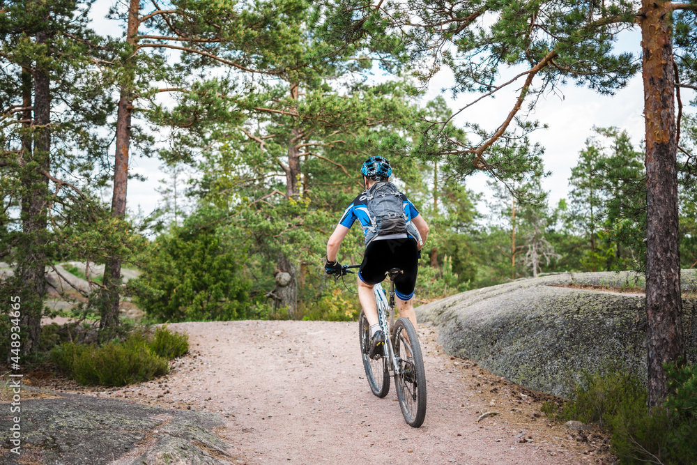 Fototapeta premium Sporty man on a mountain bike cycling on a forest trail