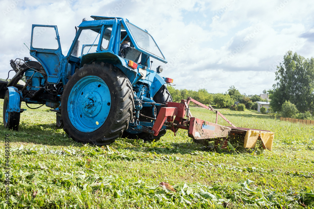 Obraz premium Old tractor with mover cutting grass in agriculture field.