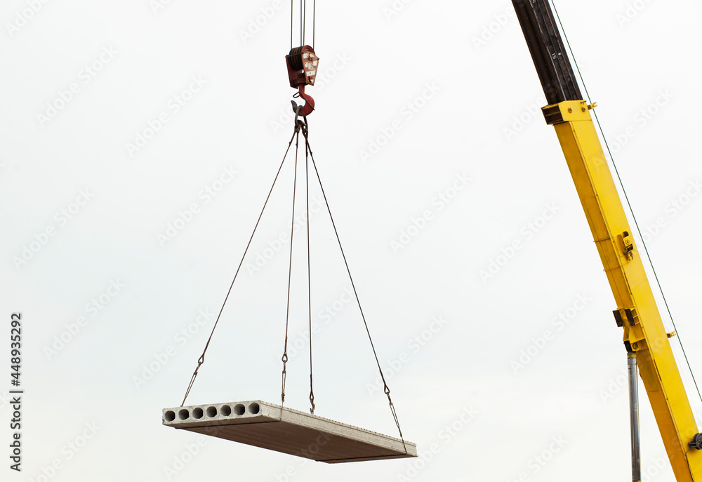The building crane lifting the concrete plate The building crane lifting the concrete plate