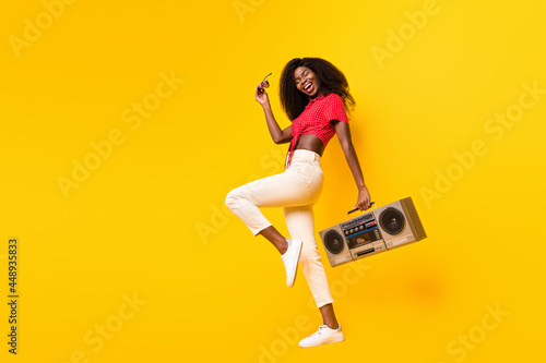 Profile photo of nice optimistic brunette lady hold boom box wear red top eyewear isolated on yellow color backgound