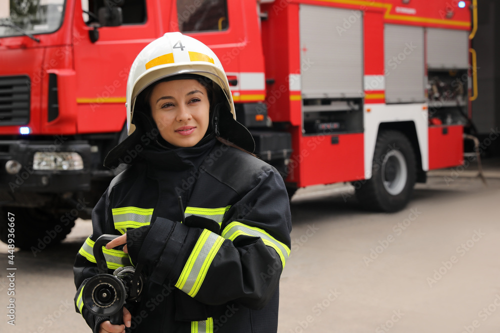 Obraz premium Firefighter in uniform with high pressure water jet near fire truck outdoors