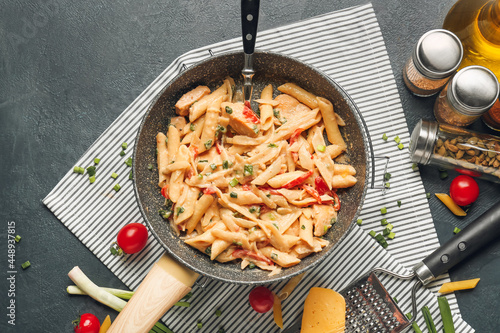 Canvas Print Composition with tasty cajun chicken pasta in frying pan on dark background