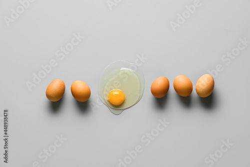 Broken egg among whole ones on grey background. Concept of uniqueness photo