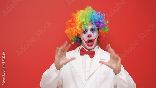 Playful clown makes grimaces on an isolated background photo