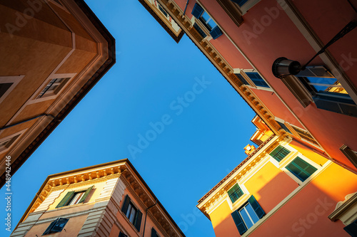 Low angle shot of old buildings in pastel colours and blue sky on Pastini street (Via dei Pastini) in historic centre of Rome, Italy