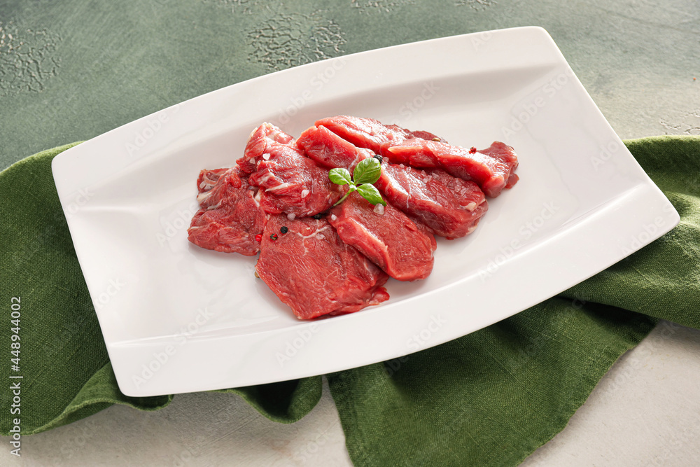 Plate with raw beef meat slices on light background Plate with raw beef meat slices on light background