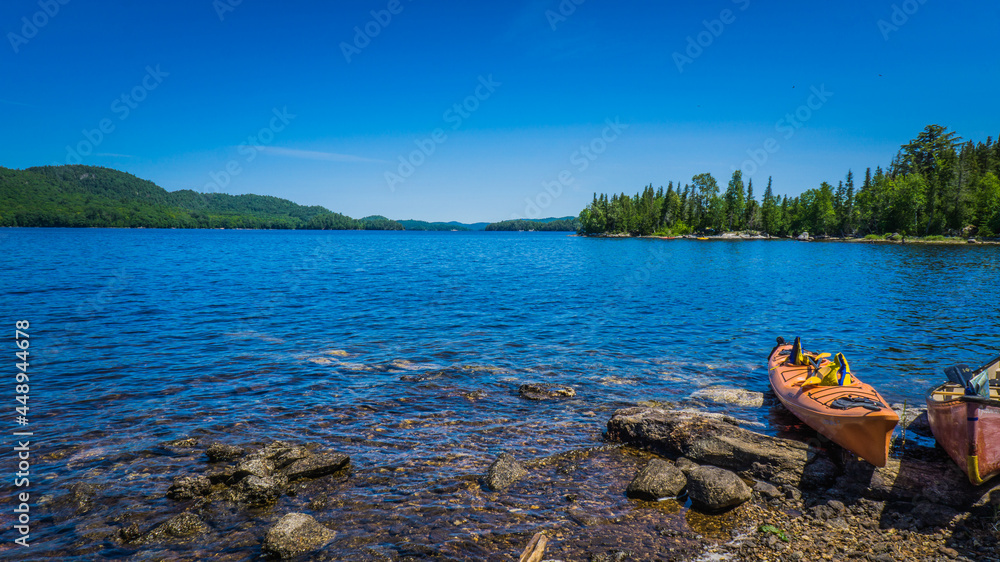 Fototapeta premium Kayak on the blue waters of the Lac du Poisson Blanc regional park (Outaouais, Quebec, Canada) on a beautiful summer day