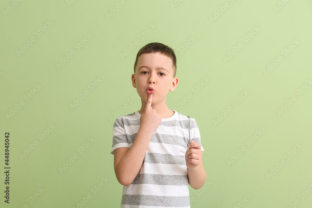 Little boy with logopedic tool for speech correction on color background - obrazy, fototapety, plakaty 
