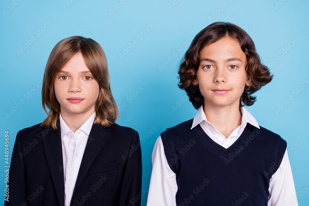 Photo portrait two schoolboys smiling in uniform isolated pastel blue color background Photo portrait two schoolboys smiling in uniform isolated pastel blue color background