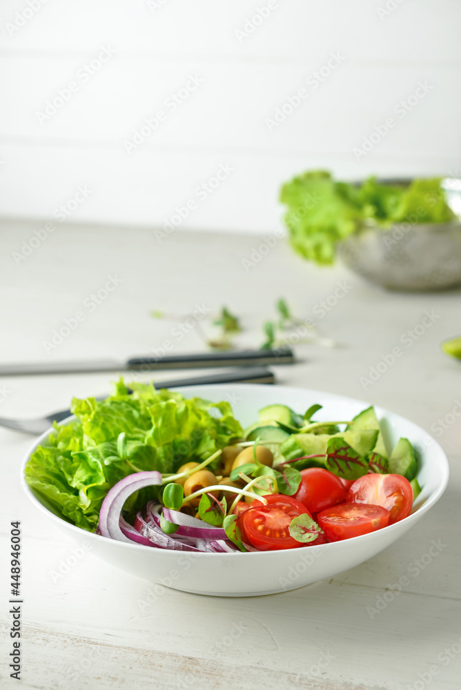 Bowl of delicious fresh salad with vegetables on white wooden table Bowl of delicious fresh salad with vegetables on white wooden table