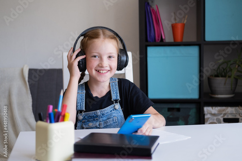  caucasian redhead girl using phone studying at home photo