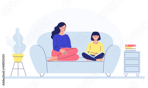 mother and child are sitting on the couch, helping to read, studying. pastime with children. family communication.