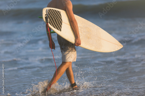 Scenic view of a surfer entering the ocean to surf huge waves during a beautiful sunset