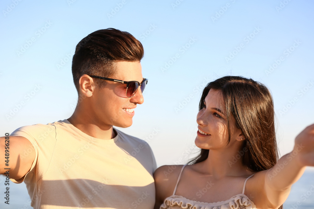 Happy young couple taking selfie on sea beach