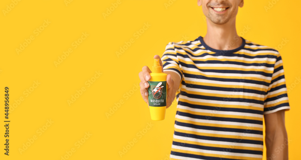 Young man with mosquito repellent on color background Young man with mosquito repellent on color background